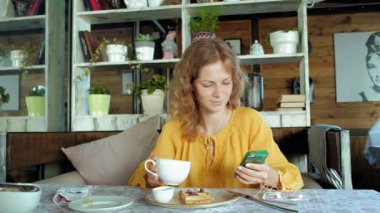 Güzel kadın bir fotoğraf çekmek için bir akıllı telefon kafe kullanımlarda Waffle yiyor