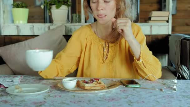 Hermosa mujer está comiendo gofres en la cafetería — Vídeos de Stock