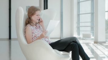 çekici işadamı Cam ofis ve kontrol belgeleri beyaz bir sandalyede oturan