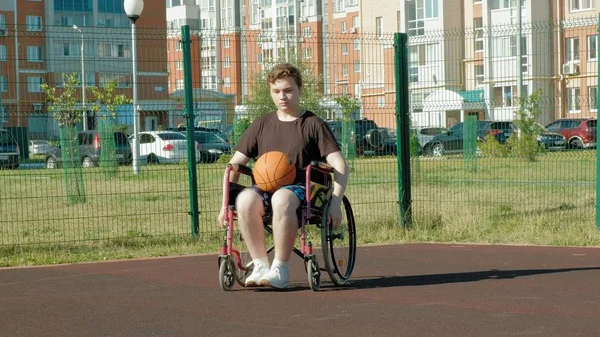 Людина з обмеженими можливостями грає в баскетбол зі свого інвалідного візка, на відкритому повітрі — стокове фото