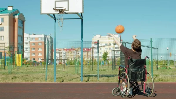 Disabled man plays basketball from his wheelchair, On open air