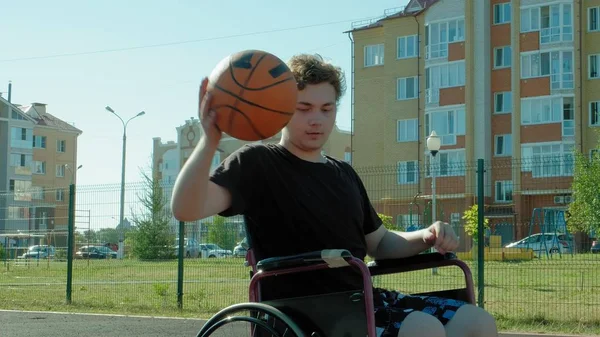 Uomo disabile gioca a basket dalla sedia a rotelle, all'aria aperta — Foto Stock