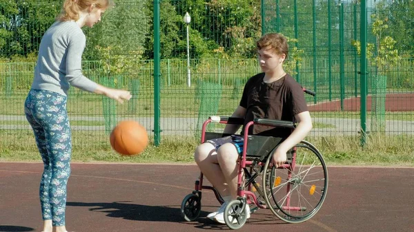 Disabled man plays basketball from his wheelchair With a woman, On open air, Make an effort when playing