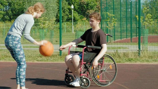 Disabled man plays basketball from his wheelchair With a woman, On open air, Make an effort when playing