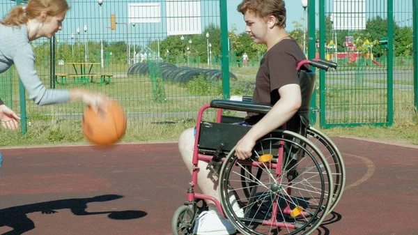 Disabled man plays basketball from his wheelchair With a woman, On open air, Make an effort when playing