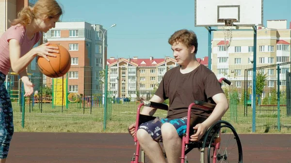 Disabled man plays basketball from his wheelchair With a woman, On open air, Make an effort when playing