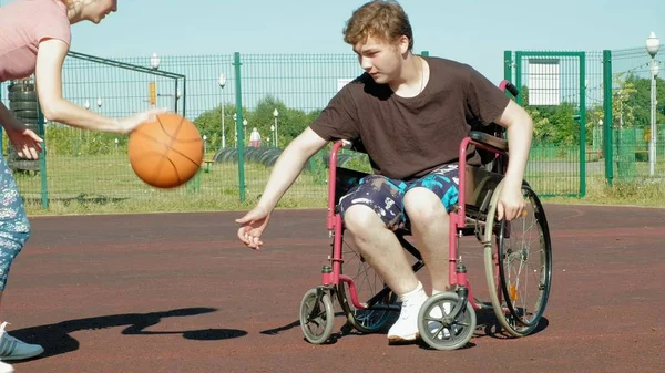 Disabled man plays basketball from his wheelchair With a woman, On open air, Make an effort when playing