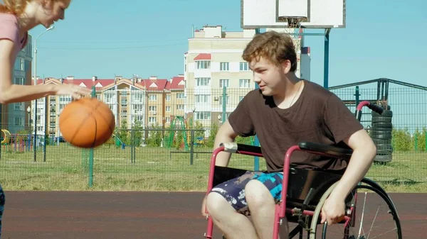 Behinderter spielt Basketball aus seinem Rollstuhl mit einer Frau, an der frischen Luft, bemühen sich beim Spielen — Stockfoto