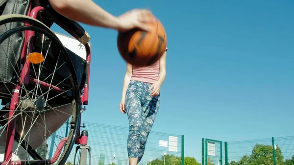 Homem com deficiência joga basquete de sua cadeira de rodas com uma mulher, ao ar livre, fazer um esforço ao jogar — Fotografia de Stock