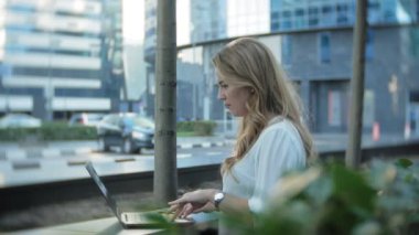 Şehir park iş merkezi içinde laptop üzerinde çalışan genç iş kadını