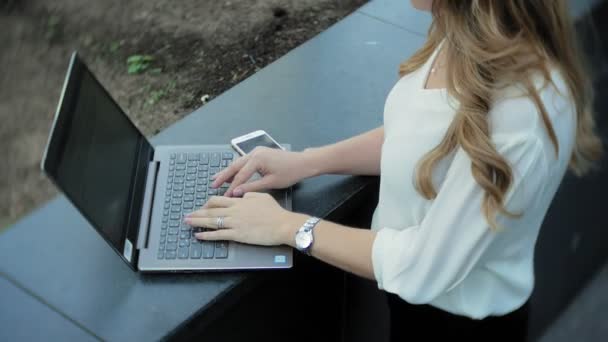 Young businesswoman working on laptop in city park business center — Stock Video