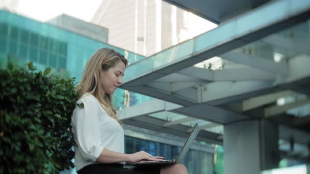 Young businesswoman working on laptop in city park business center — Stock Video