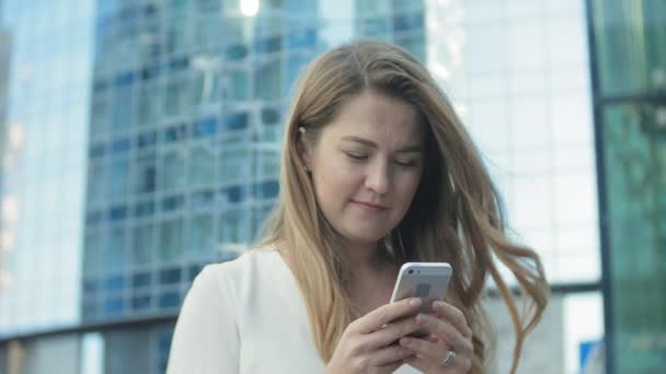 Joven mujer de negocios hablando está utilizando el teléfono inteligente en el centro de negocios del parque de la ciudad — Vídeos de Stock