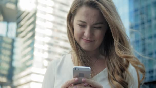 Joven mujer de negocios hablando está utilizando el teléfono inteligente en el centro de negocios del parque de la ciudad — Vídeos de Stock