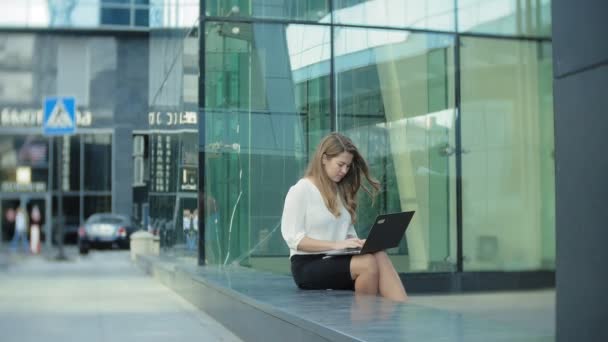 Молода бізнес-леді працює на ноутбуці в діловому центрі міського парку — стокове відео