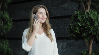 Genç işkadını konuşmak smartphone şehir park iş merkezinde kullanıyor