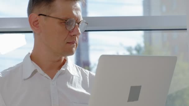 Rijpe zakenman in een venster met een laptop — Stockvideo