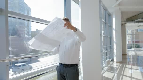 Hombre de negocios maduro en una ventana con un escanea un dibujo en papel — Vídeos de Stock