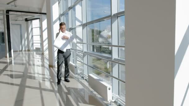 Reifer Geschäftsmann am Fenster mit einer Zeichnung auf Papier — Stockvideo