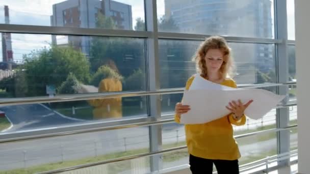 Fiatal szép üzletasszony, az ablak-val egy vizsgál egy rajz papírra — Stock videók