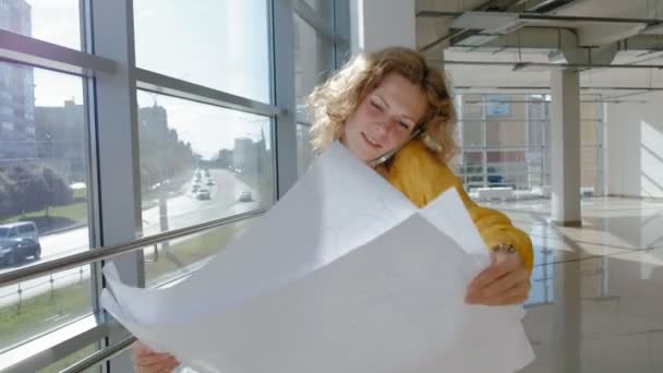 Junge schöne Geschäftsfrau, am Fenster mit einem Scanner eine Zeichnung auf Papier — Stockvideo