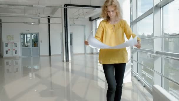 Jeune belle femme d'affaires, par la fenêtre avec un scans un dessin sur papier — Video