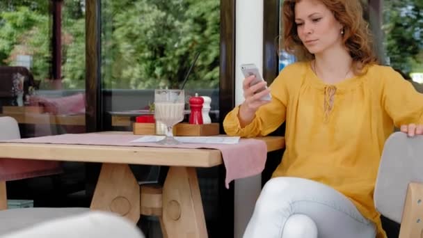 一个漂亮的年轻女人在咖啡馆里喝着冰沙 — 图库视频影像