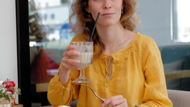 Gyönyörű fiatal nő eszik reggeli tojás pirítóssal, egy kávézóban — Stock videók