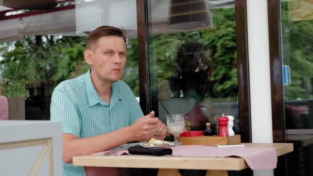 Зрілий чоловік їсть сніданок з тостів з яйцями в кафе — стокове відео