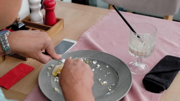 Älterer Mann isst Frühstück aus Toast mit Eiern in einem Café — Stockvideo