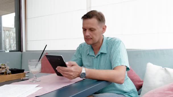 Зрелый мужчина с сенсорным экраном планшетного компьютера в кафе — стоковое видео