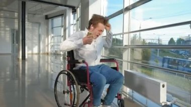 adam bir smartphone--dan kulaklıklar müzik dinlemek bir pencere, bir tekerlekli sandalye üzerinde devre dışı