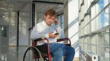 adam bir smartphone--dan kulaklıklar müzik dinlemek bir pencere, bir tekerlekli sandalye üzerinde devre dışı