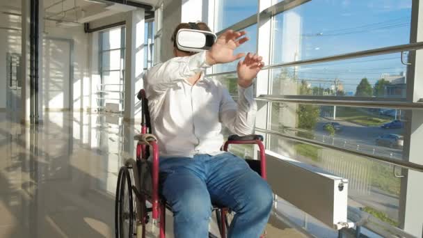 Ανάπηρο άνθρωπο σε αναπηρικό καροτσάκι σε ένα παράθυρο χρησιμοποιεί ένα κράνος εικονικής πραγματικότητας — Αρχείο Βίντεο