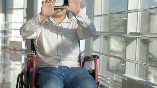 Funktionshindrade människan på en rullstol på ett fönster använder hjälm av virtuell verklighet — Stockvideo