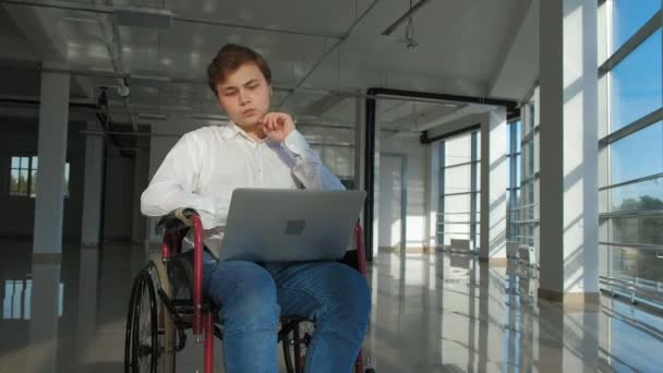 Handicap zakenman op een rolstoel in een venster met een laptop — Stockvideo