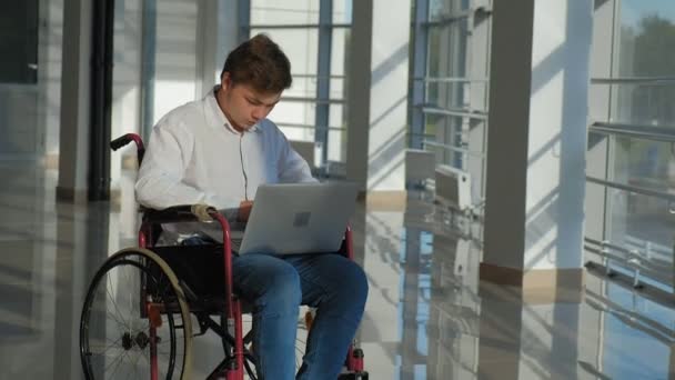 Behinderter Geschäftsmann im Rollstuhl am Fenster mit Laptop — Stockvideo