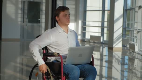 Άτομα με ειδικές ανάγκες επιχειρηματίας σε μια αναπηρική καρέκλα σε ένα παράθυρο με έναν φορητό υπολογιστή — Αρχείο Βίντεο