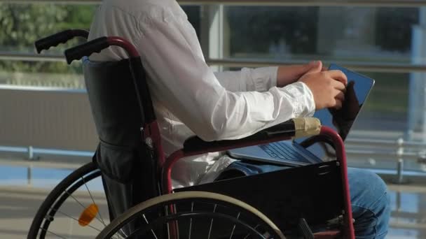 Handicap zakenman op een rolstoel in een venster met een laptop — Stockvideo