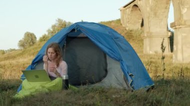 Bir dizüstü bilgisayar eski Köprüsü yakınlarında bir turist çadırda arkasında çalışan genç kadın