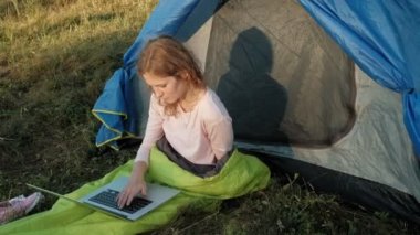 Bir dizüstü bilgisayar bir turist çadırda arkasında çalışan genç kadın