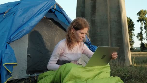 在旧桥附近的旅游帐篷里工作的年轻女子的笔记本电脑后面 — 图库视频影像