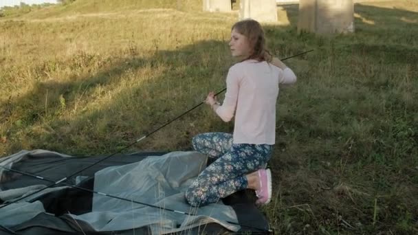 若い女性は、古い橋の近くの観光テントを収集します。 — ストック動画