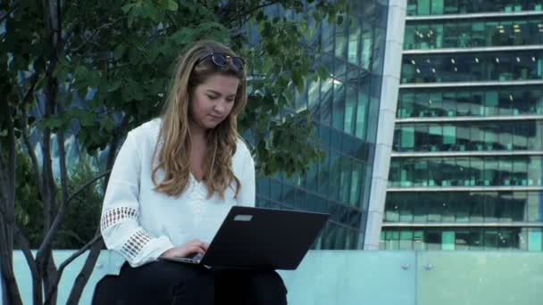 Joven empresaria trabajando en la computadora portátil en el parque de la ciudad — Vídeos de Stock