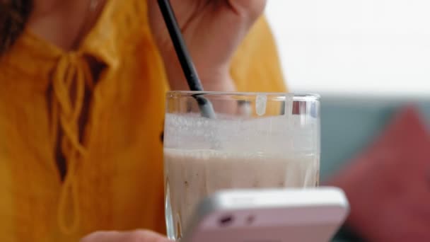 Une belle jeune femme boit un smoothie dans un café — Video