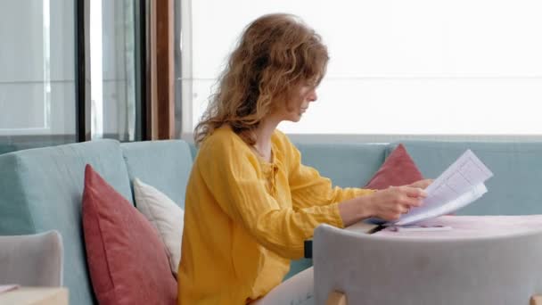 Frumoasă femeie tânără navighează documente într-o cafenea — Videoclip de stoc