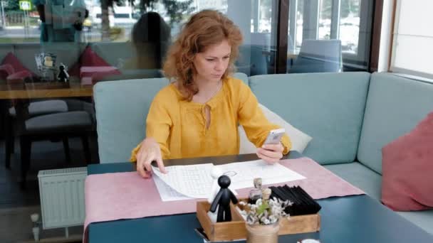 Beautiful young woman browsing documents in a cafe — Stock Video