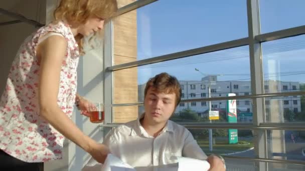 Disabled businessman on a wheelchair in a window with a picture on a large sheet of paper discussing work with a business woman, discussion in the office... — Stock Video