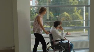 Telefonda konuşan bir tekerlekli sandalye Engelli bir işadamı ile bir tekerlekli sandalye üzerinde wheeling iş kadını