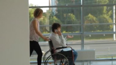 Telefonda konuşan bir tekerlekli sandalye Engelli bir işadamı ile bir tekerlekli sandalye üzerinde wheeling iş kadını